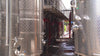 large aluminium wine barrels with red industrial hoses